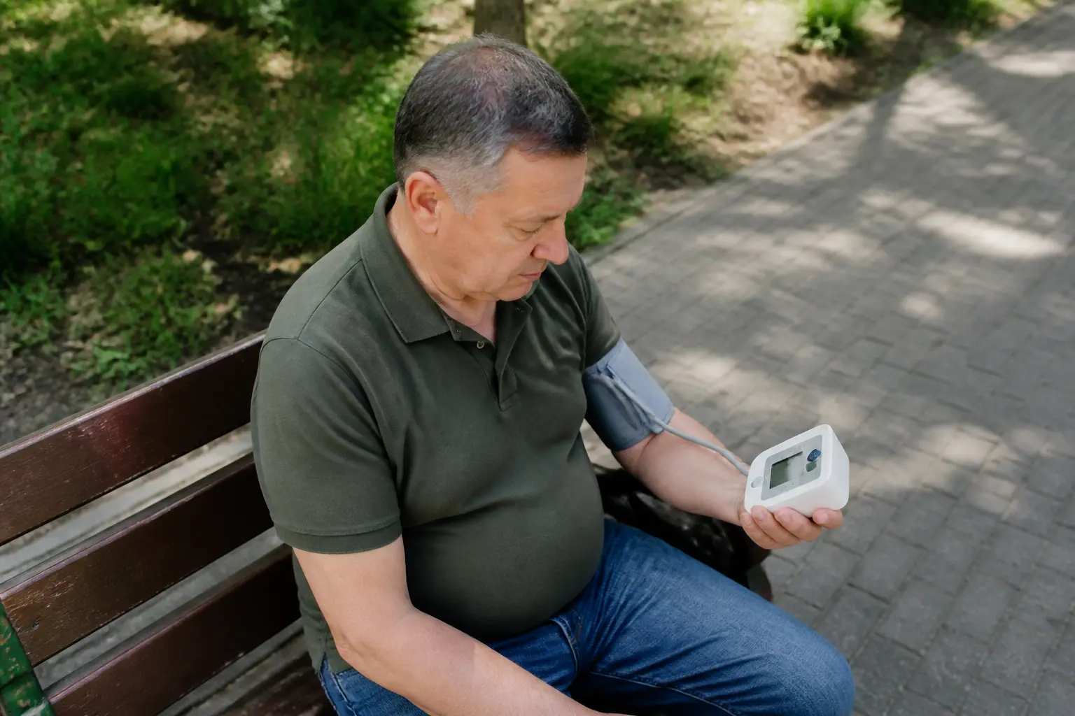 Чоловік середнього віку вимірює тиск на лавці в парку